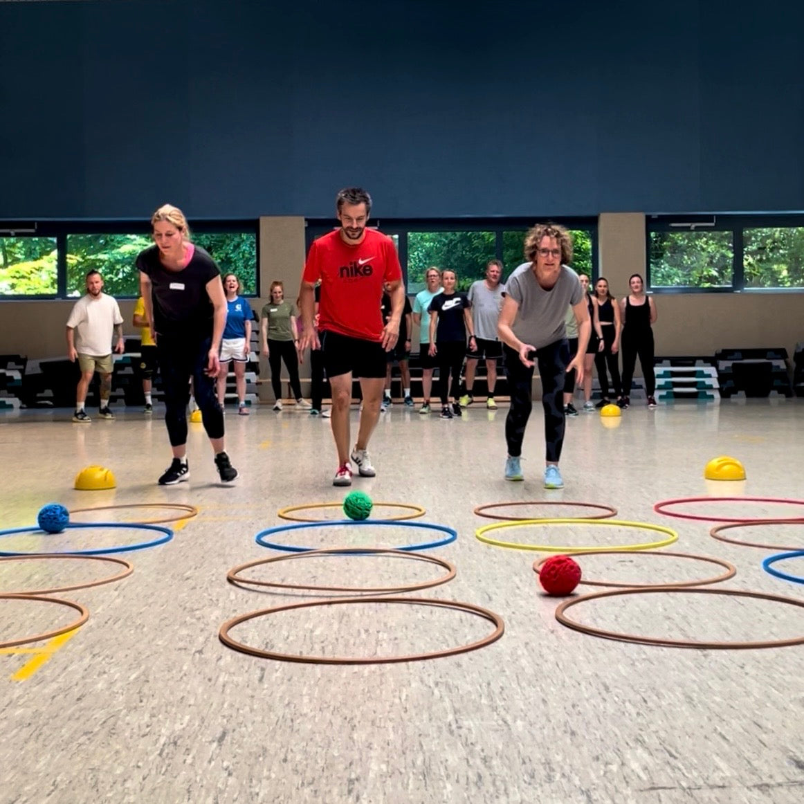 Kinder rollen in der Sporthalle Trockene Schneebälle in eine Reihe aus Reifen