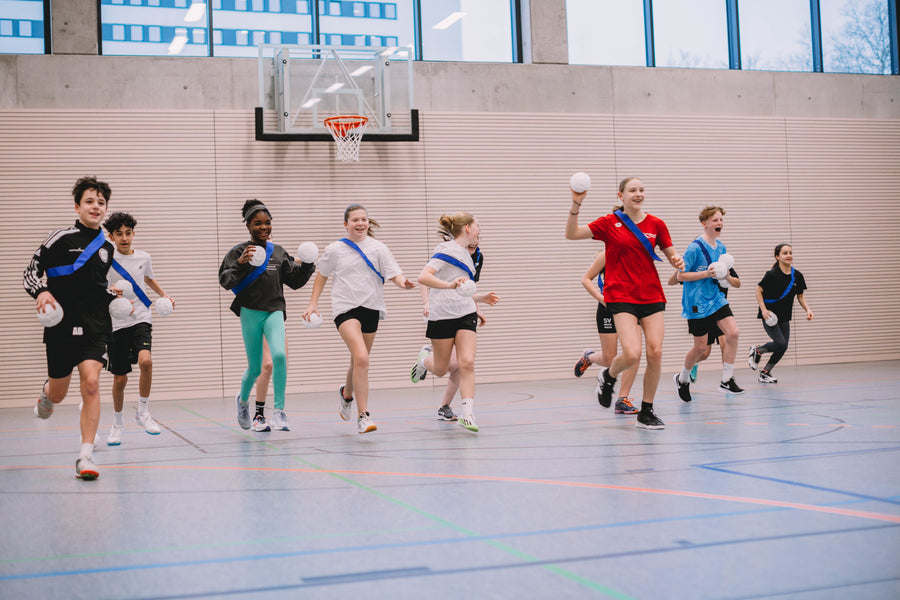 Kinder werfen sich in der Sporthalle mit vielen weichen Bällen ab